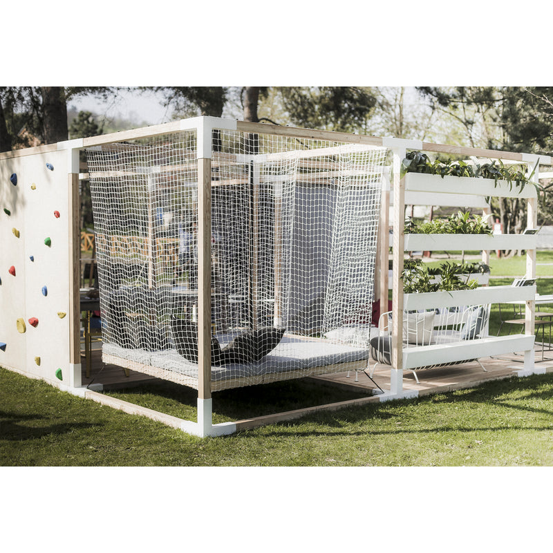 Leva Home by Egoe is a modern outdoor play area with a climbing wall, suspended nets, vertical planter boxes, and elegant outdoor furniture. Set in a grassy park with trees, sunlight filtering through creates a tranquil and relaxing atmosphere.