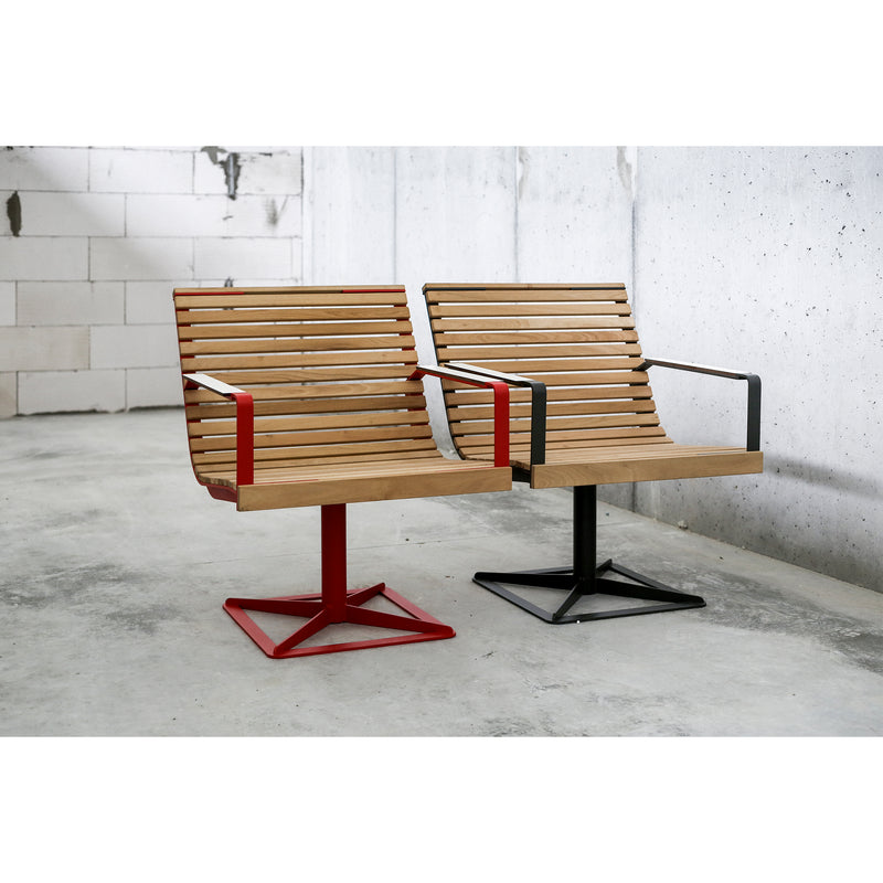 Two Egoe Preva Armchairs with wooden slats and metal frames sit side by side on a concrete floor against a light gray wall. One has a red frame, the other black, showcasing sophisticated design and durability.