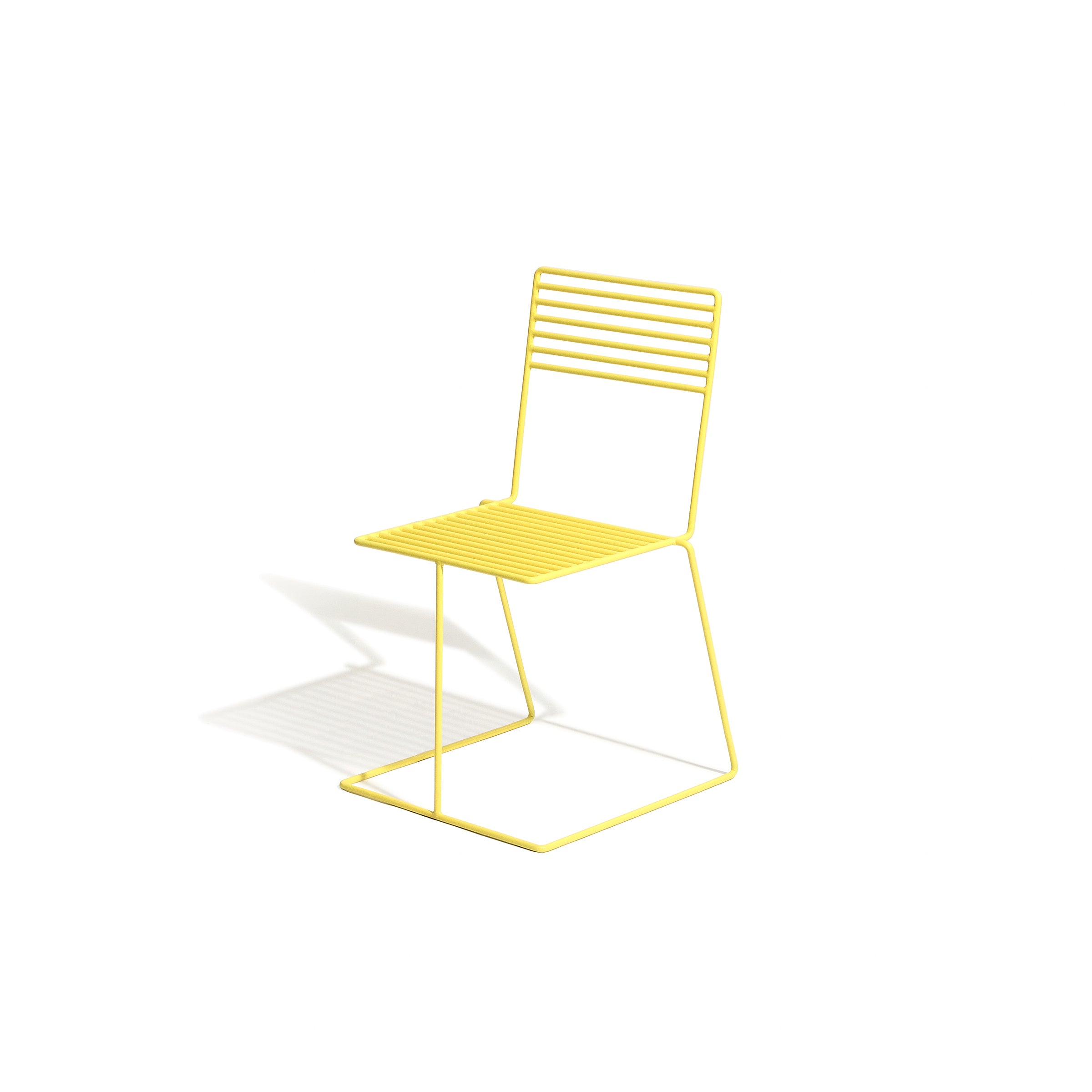 The Tina Chair by Egoe is a modern minimalist piece with a yellow metal wireframe design and powder-coated finish. Its suspended seat and backrest feature horizontal bars, elegantly resting on three legs, casting a shadow on the pristine white background.