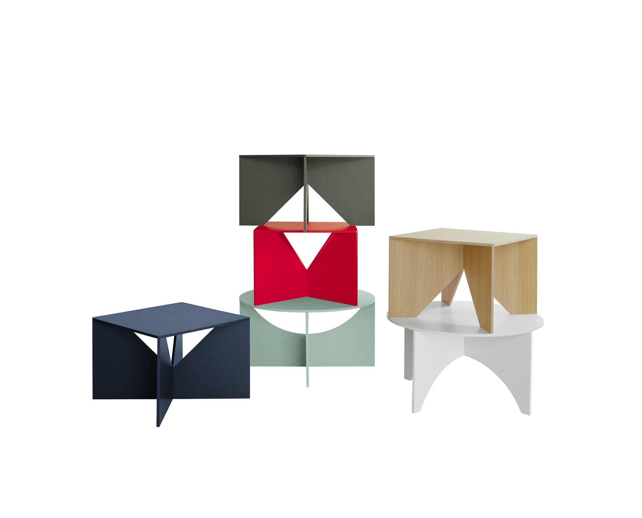 The FK04 CALVERT collection by E15 features modern geometric coffee tables with folded, intersecting designs in blue, gray, red, light green, wood, and white. Inspired by Ferdinand Kramers visionary style, these knock-down pieces stack creatively against a plain white background.