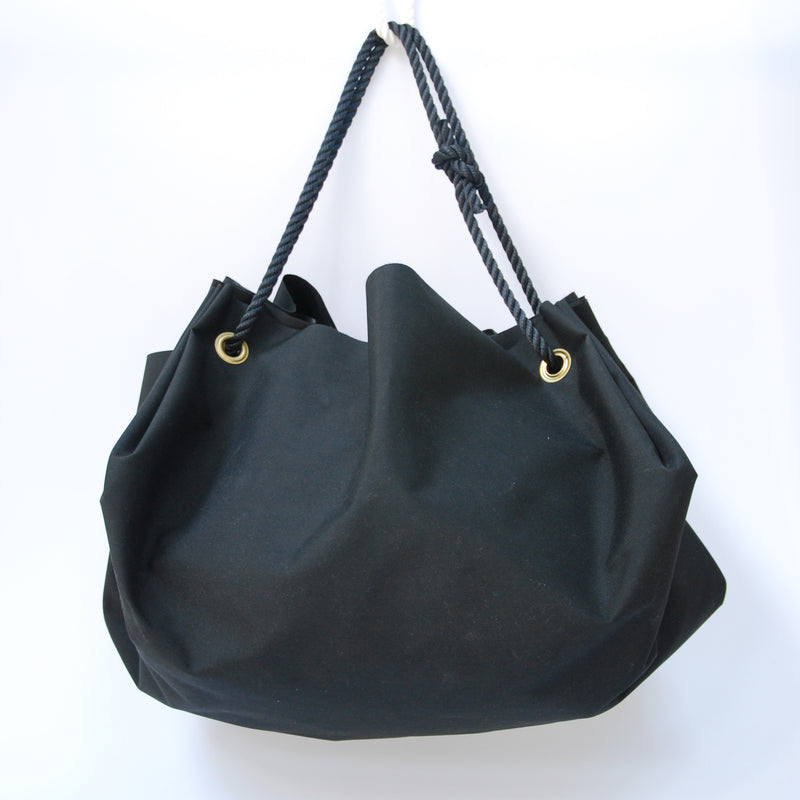 The Big Bag by GoodGoods is a large, sturdy, waterproof duffle bag featuring gold grommets and navy rope handles, showcased against a plain white background.