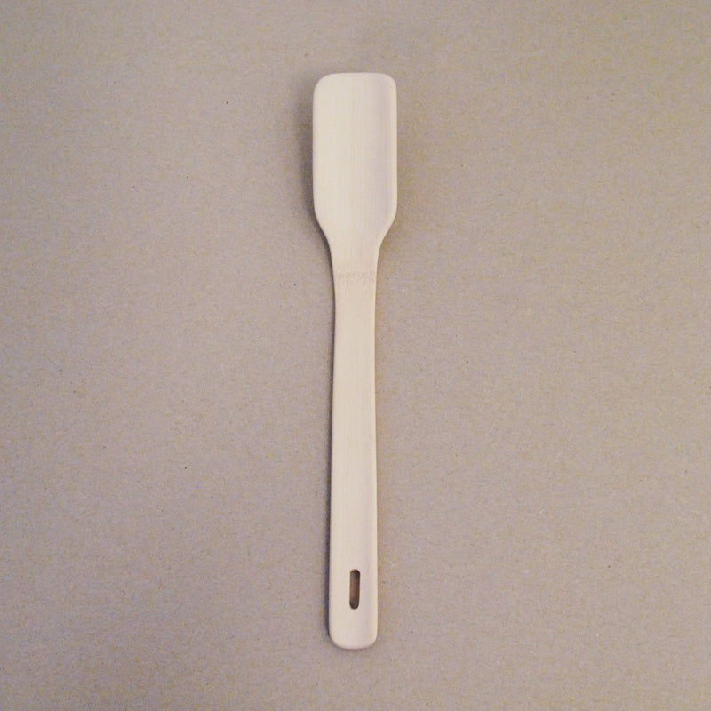 The GoodGoods Goodspoon is a bamboo-crafted wooden spatula with a rectangular head, long handle, and a small hanging hole, showcased on a light-colored surface.