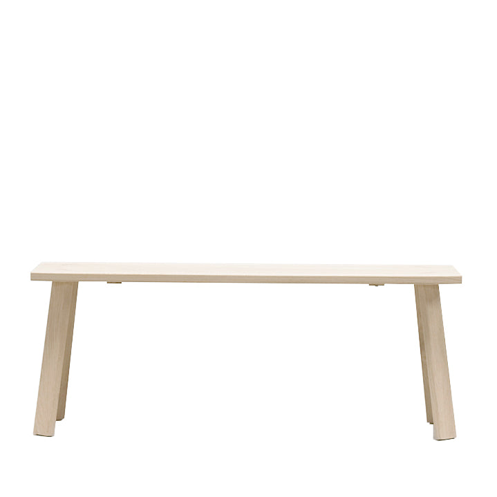 The Alpin Table by Hussl is a simple, minimalist design with a light wood finish. Its flat horizontal surface and four angled legs are perfect for indoor settings, and the white background enhances its elegance.