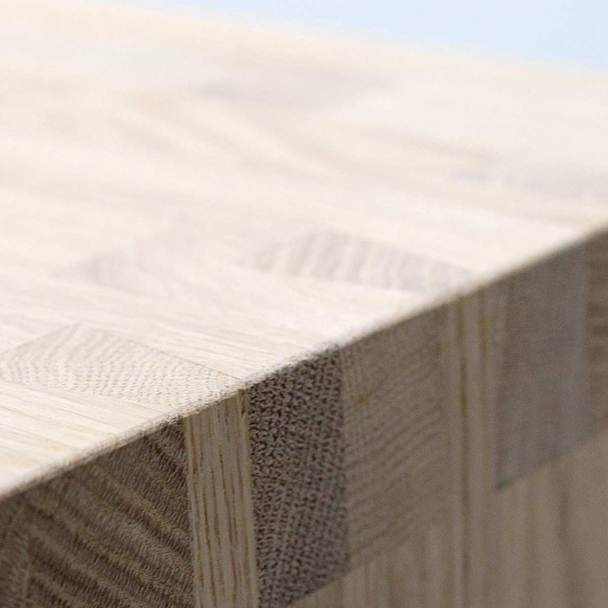 Close-up of the Hussl benchs wooden tabletop with smooth, light-colored grain. The edge showcases a visible dovetail joint, emphasizing the natural textures and craftsmanship typical of Hussl furniture.