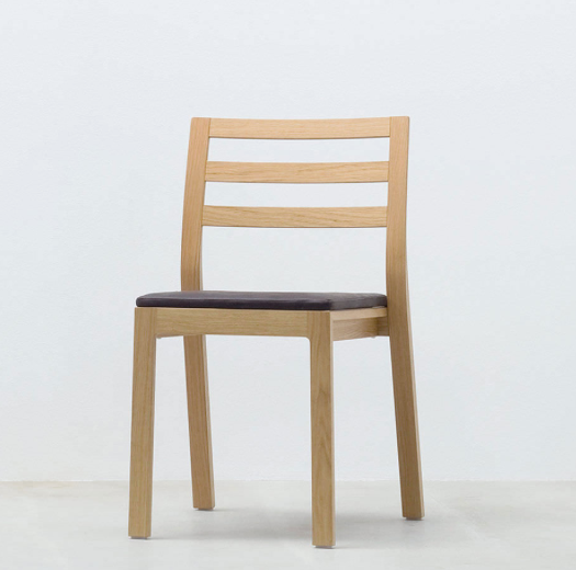 The ST10 - Upholstered chair by Hussl, crafted with advanced sandwich technology and a light oak finish, features a slatted back and dark cushioned seat. It rests elegantly on a plain white background.