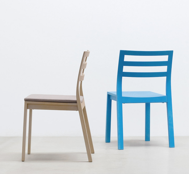 Two minimalist chairs: one wooden with a beige cushion, made from wood composite for durability, side view; the other is a bright blue Hussl ST10 - Upholstered chair, back view. Both feature ladder-style backs on a light floor against a white wall.