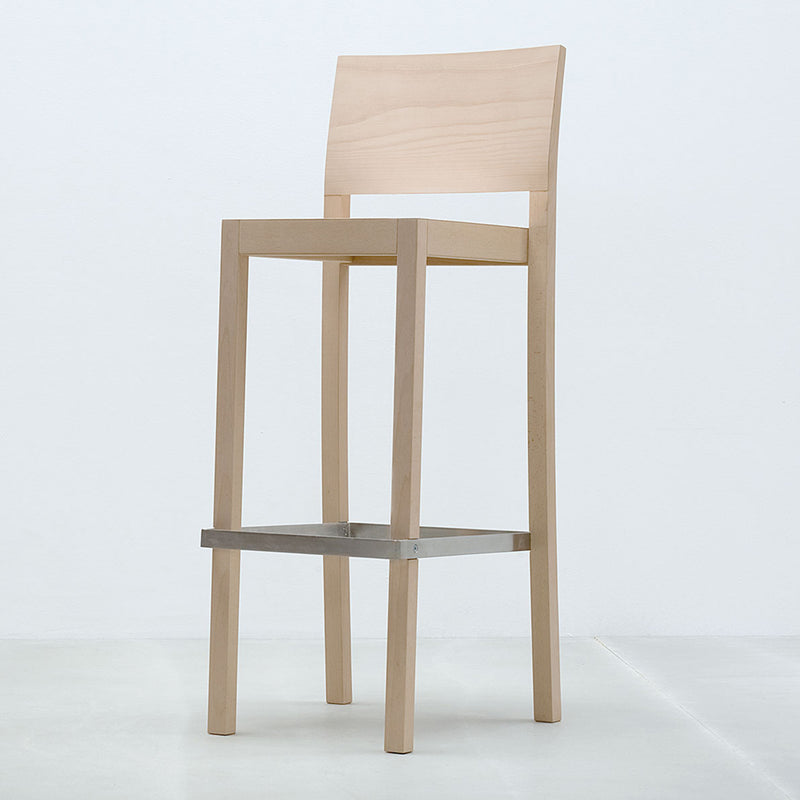 The ST4N Barstool by Hussl, featuring a minimalist natural wood design with classic contours and a square metal footrest, has a straight backrest and four sturdy legs for high comfort, all set against a plain white background.