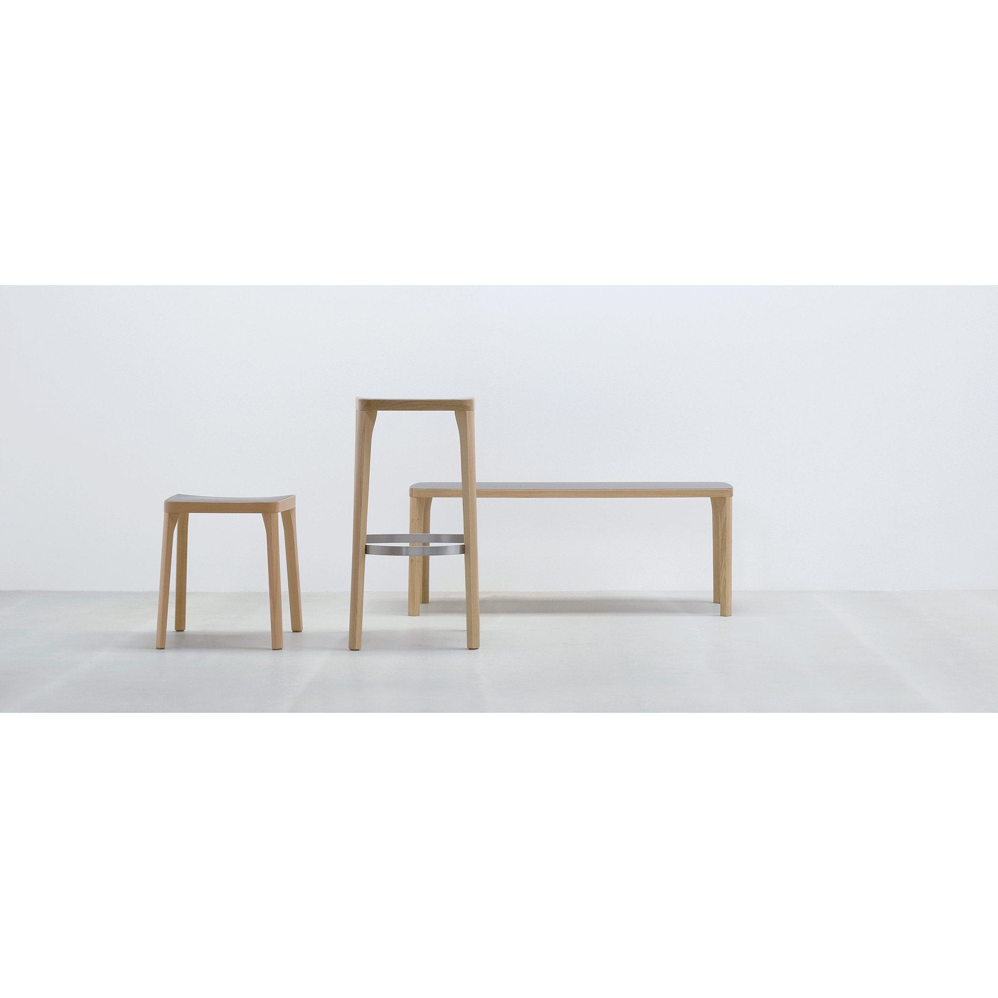 A minimalist scene presents three wooden seating options: a small stool, the Hussl ST6N-0 Barstool with Austrian coffee house flair, and a long backless bench. Each piece has clean lines and a natural wood finish on a plain white background, showcasing modern elegance.