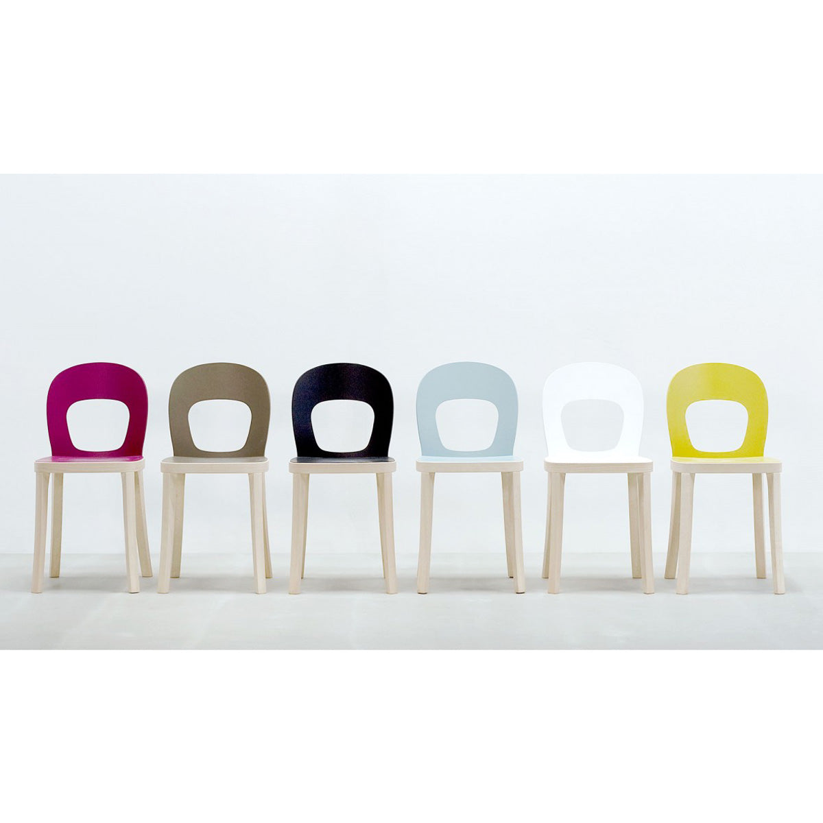 Six Hussl ST6N-1 chairs with wooden legs are lined up against a light backdrop, reminiscent of classic Austrian coffee house settings. They have rounded backrests in magenta, brown, black, light blue, white, and yellow finishes and are both stable and functional.