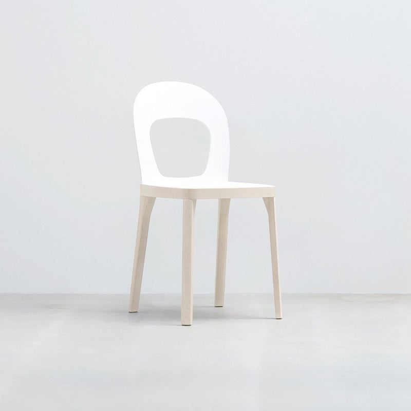 The ST6N-1 by Hussl is a minimalist white chair featuring a circular open backrest, four straight legs, and a flat seat. Reminiscent of Austrian coffee house furnishings, it offers stability and elegance against a plain white background.