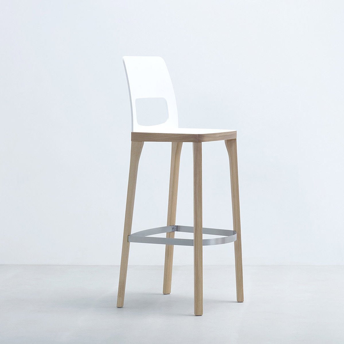 The Hussl ST6N-2 Barstool features a white plastic backrest with a rectangular cutout, light wood legs, and a metal footrest. Reminiscent of Austrian coffee house design, it complements any minimalist setting with its elegant appearance.