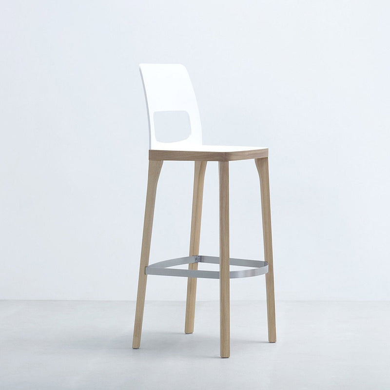 The Hussl ST6N-2 Barstool features a white plastic backrest with a rectangular cutout, light wood legs, and a metal footrest. Reminiscent of Austrian coffee house design, it complements any minimalist setting with its elegant appearance.