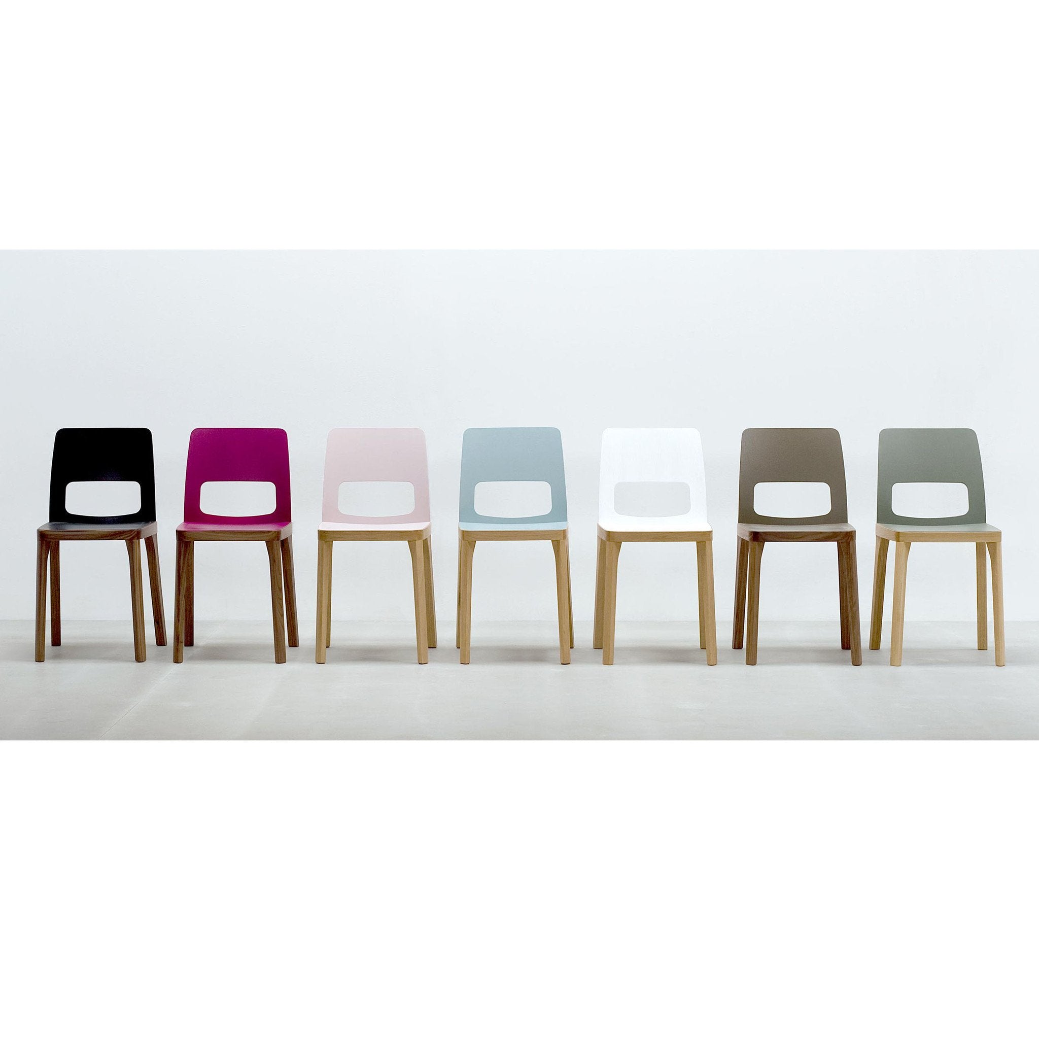 A row of seven elegant Hussl ST6N-2 chairs with wooden legs and vibrant seats in black, purple, light pink, light blue, white, brown, and dark green offers enchanting color combinations reminiscent of classic Austrian coffee house furniture.