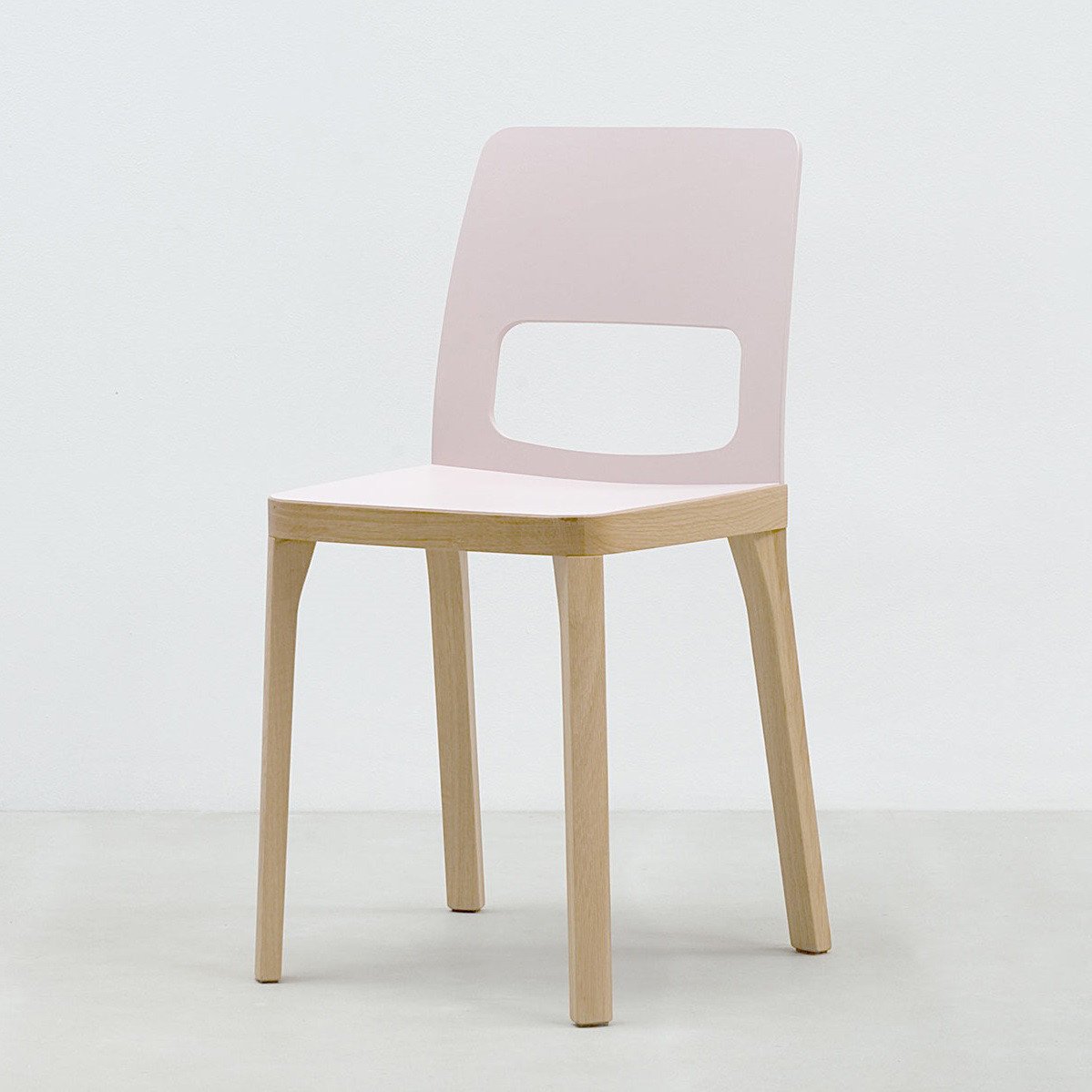 The Hussl ST6N-2 chair features a minimalist design with a light wooden frame and legs, echoing Austrian coffee house style. Its pale pink seat and backrest include a chic rectangular cutout on the lower backrest, all displayed against a plain white background for added elegance.