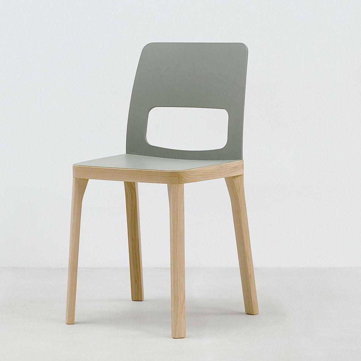 The ST6N-2 by Hussl is a modern chair featuring a light wooden frame, sleek gray seat and backrest, and a rectangular cutout. Inspired by Austrian coffee house elegance, it rests on four straight legs, all set against a plain white background.