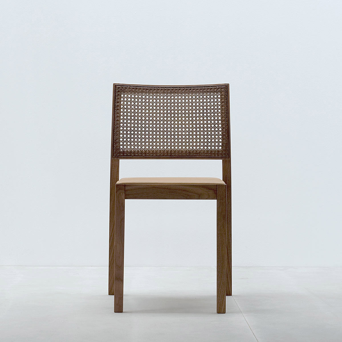 The ST4N Gritsch chair by Hussl features a wooden frame with a light brown Viennese weave backrest and a smooth, light-toned seat. It is set against a light gray backdrop on a white floor, reflecting the simple, modern style of coffeehouse furniture.