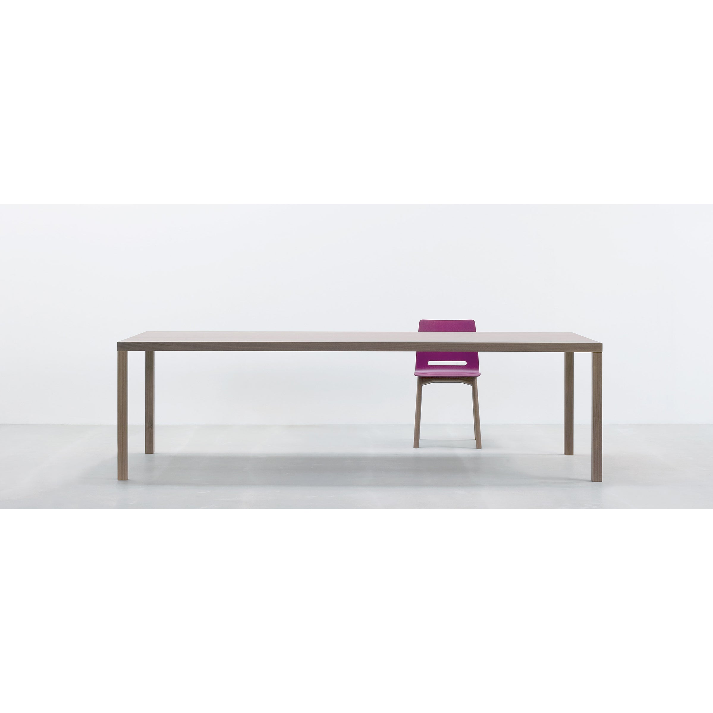 A minimalist room showcases the Hussl TC4, a long, rectangular wooden table paired with a single purple chair, perfect for business settings. The plain white background sharply contrasts with the furnitures durable surfaces.