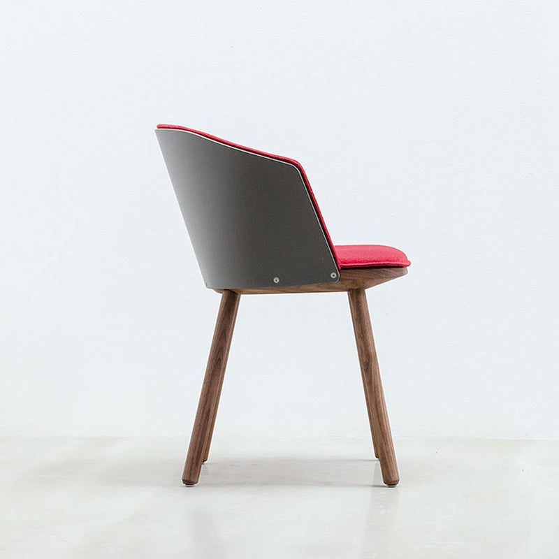 Side view of a Hussl Lino C armchair with a gray back, red cushioned seat, and natural wooden legs, set against a plain white background. The chair showcases an elegant design with ergonomic comfort.