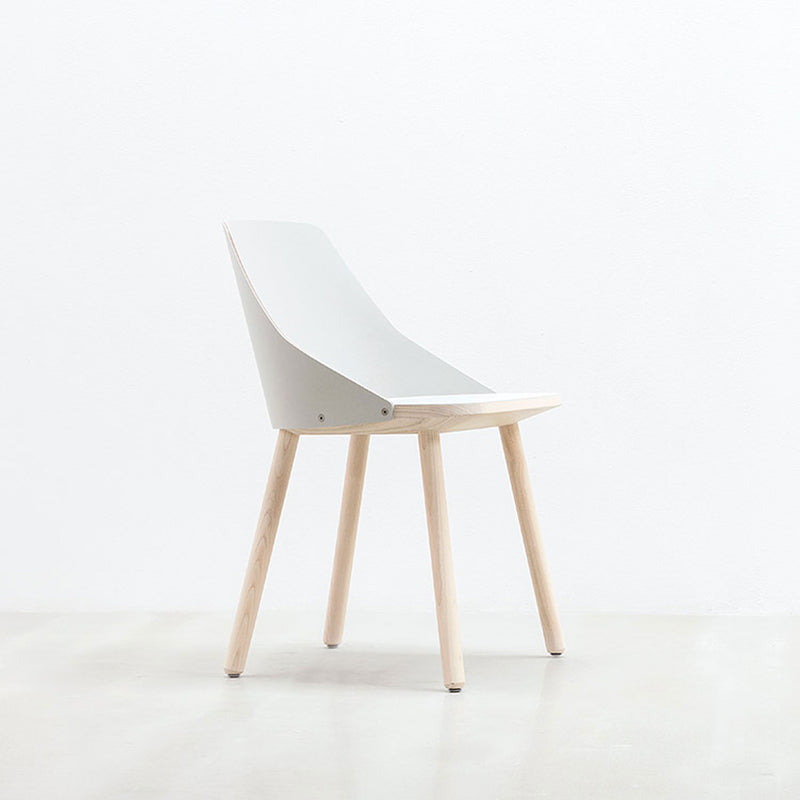 The Lino C chair by Hussl features a minimalist design with a light gray, curved backrest and seat, supported by four light wooden legs made from natural materials. It sits on a pale floor against a simple white wall.