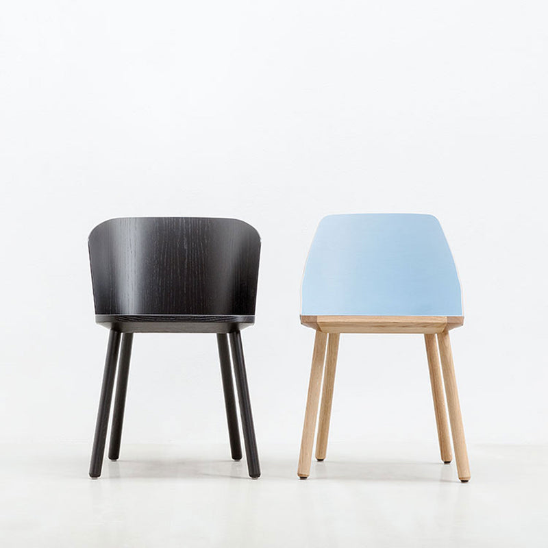 Two minimalist chairs against a white background: the left features Hussls Lino C, a dark wood shell chair with a curved back. The right showcases light blue upholstery and natural wood legs, both embodying simple, modern design.