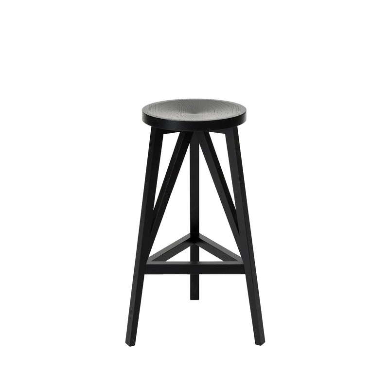 The JL4 Faber Barstool by Loehr features a modern, round black base with a solid oak seat and four legs connected by diagonal supports, showcasing a unique silhouette inspired by northern European architecture, set against a pristine white background.