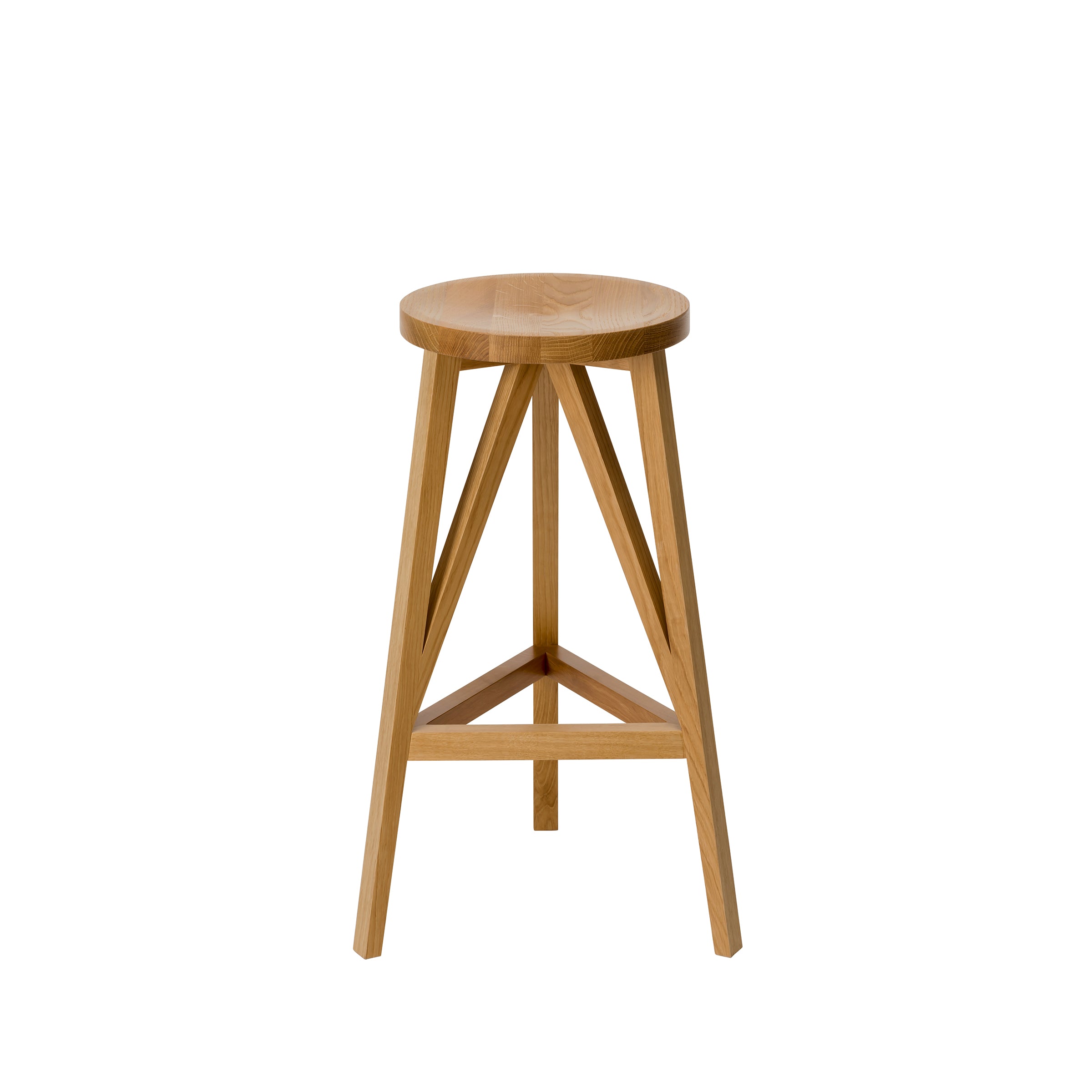The JL4 Faber Barstool by Loehr features a round seat and three angled legs with triangular supports in solid oak. Its natural finish and simplified design are inspired by northern European architecture, offering a minimalist, modern look with a distinctive silhouette.