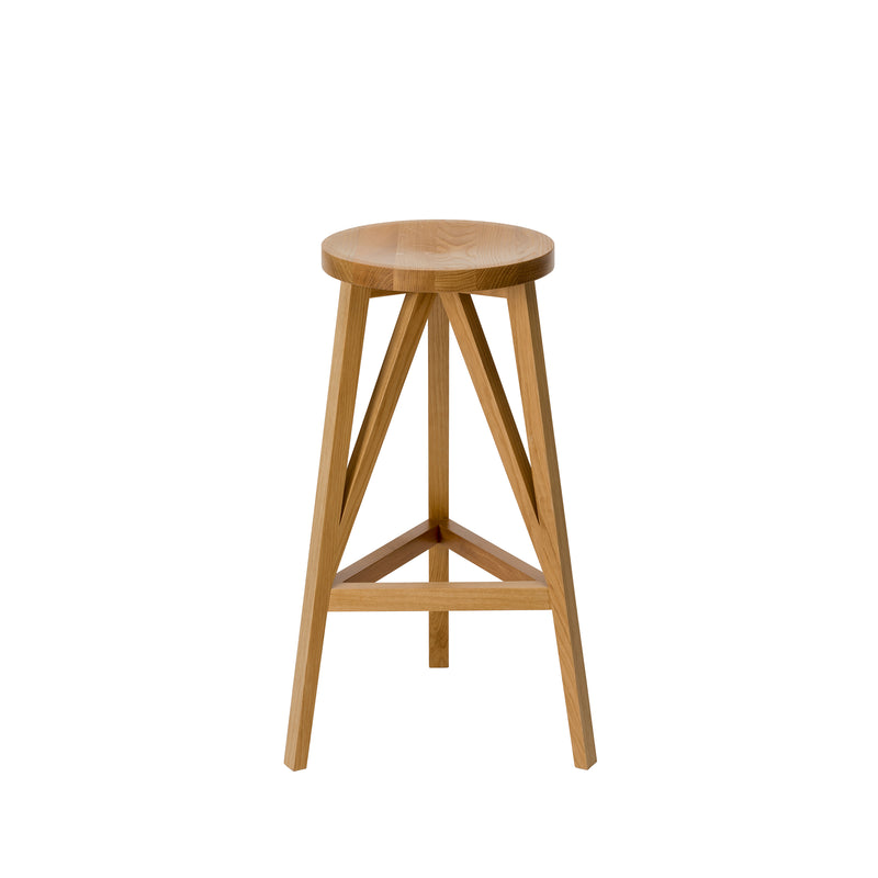 The JL4 Faber Barstool by Loehr features a round seat and three angled legs with triangular supports in solid oak. Its natural finish and simplified design are inspired by northern European architecture, offering a minimalist, modern look with a distinctive silhouette.