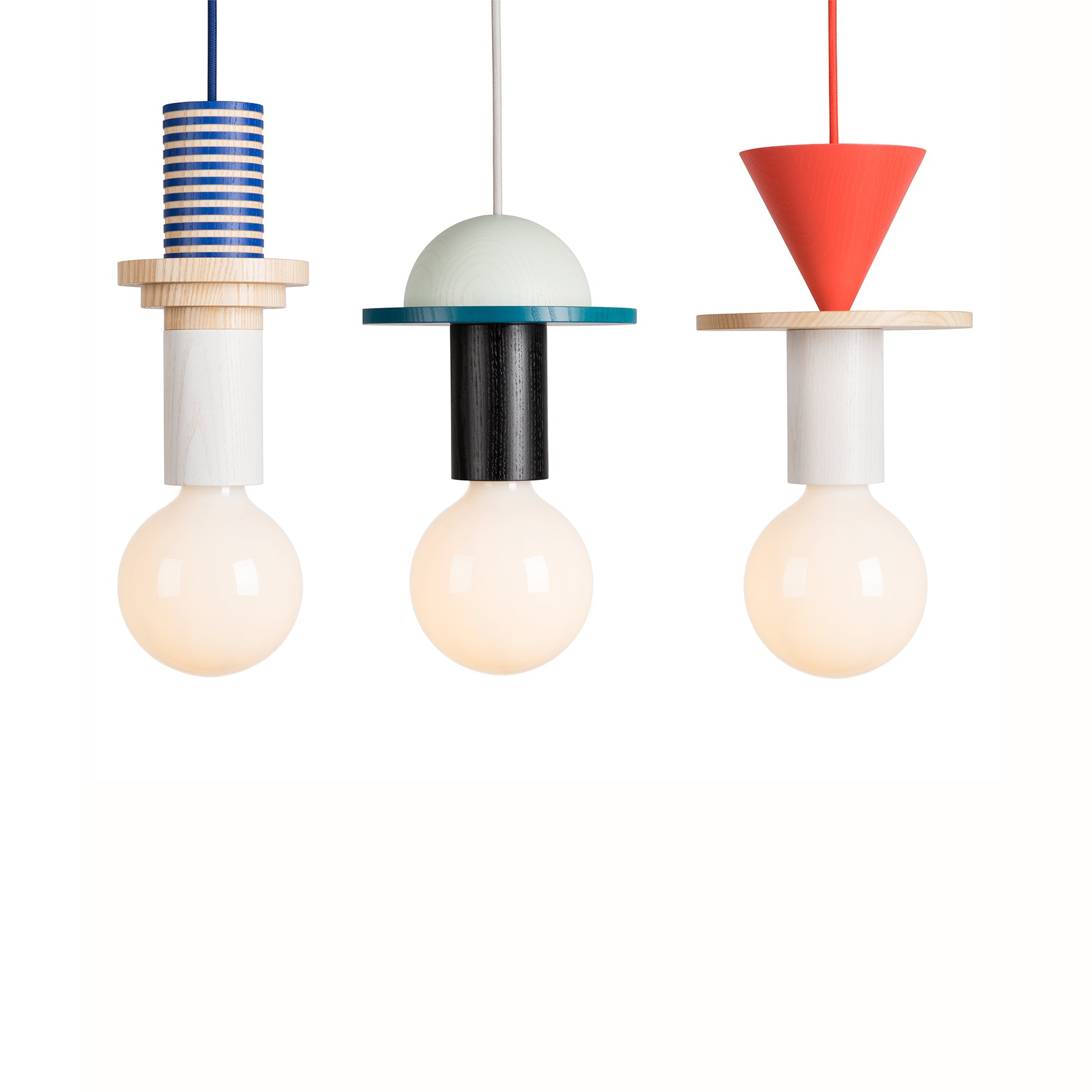 The Junit Crescent by Schneid features three geometric modular pendant lamps: a blue-striped left, a green dome center, and a red cone right. Each offers ambient light from large white bulbs below and is crafted from high-quality ash wood for added elegance.
