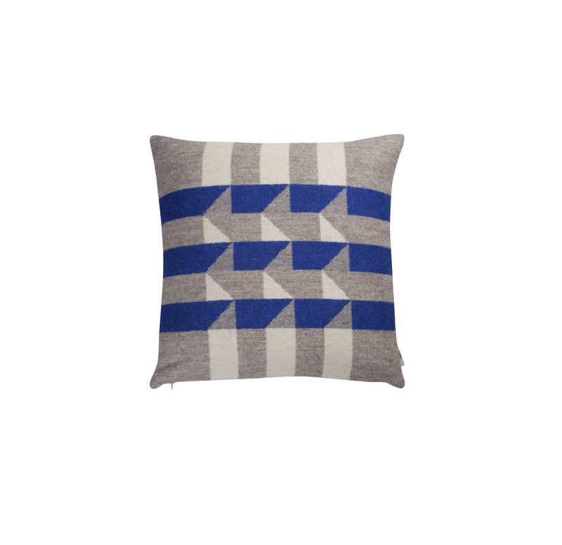 The Kvam Cushion by Roros is a square cushion made from Norwegian lambswool, showcasing a dynamic visual with blue, white, and gray interlocking geometric patterns.