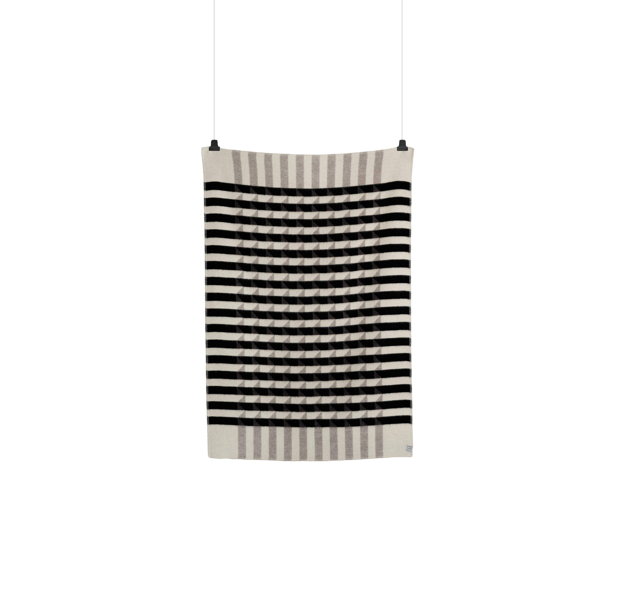 The Kvam Large Throw by Roros is a wool blanket with a jacquard weave, showcasing horizontal black and white geometric stripes, black circular designs, and bordered by gray and white stripes. It hangs with two clips against a plain background.