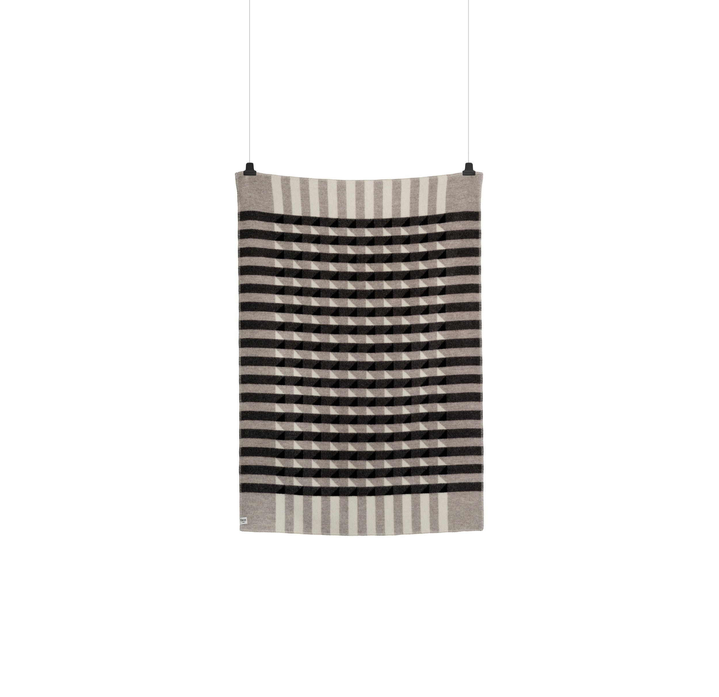 The Kvam Large Throw by Roros is a rectangular jacquard weave textile with vertical black and gray stripes, featuring a central geometric design. Hanging from two clips against a plain white background, it embodies the elegance typical of wool blankets.