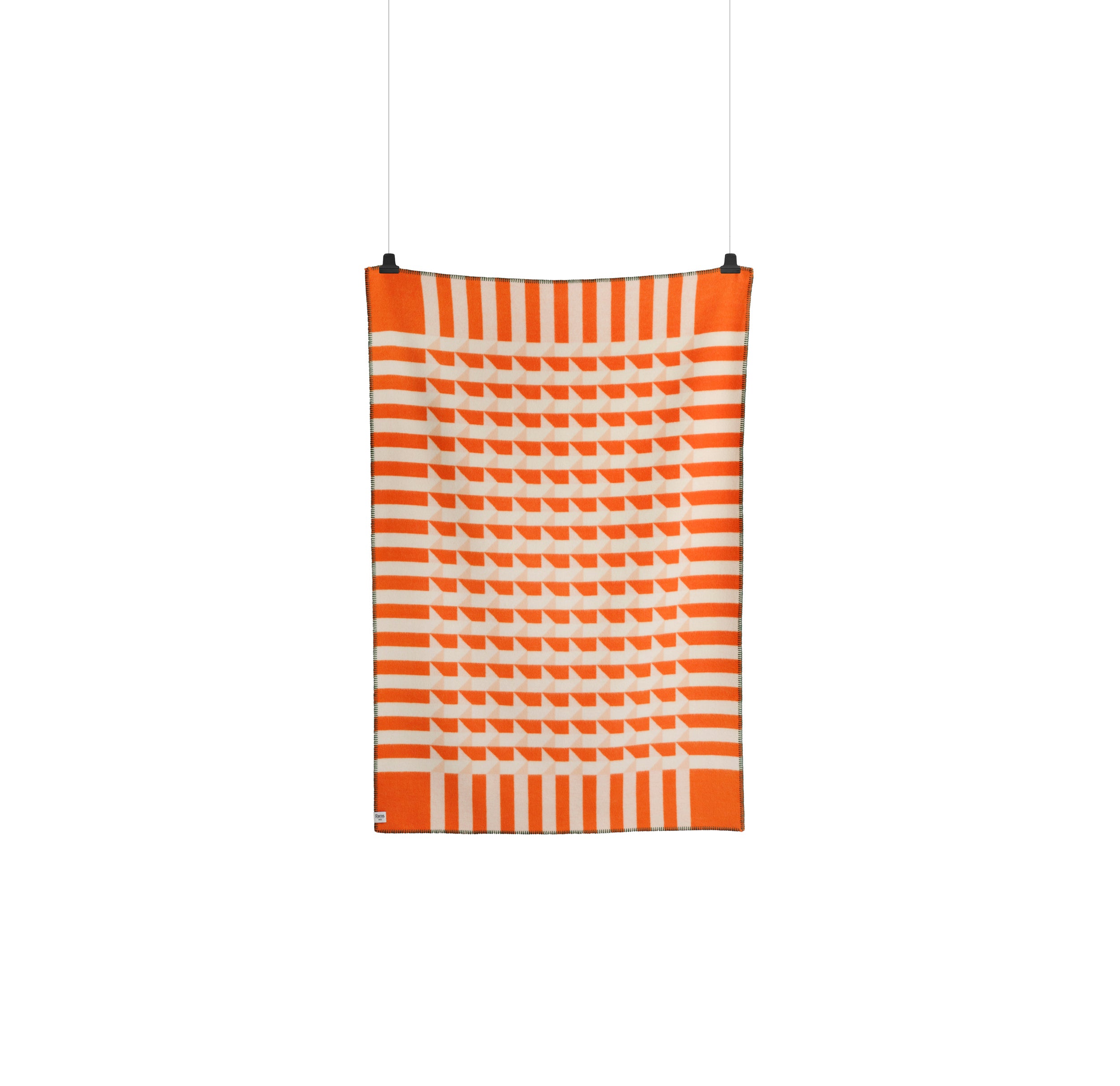 The Kvam Large Throw by Roros, showcasing orange and white geometric patterns and striped borders in a jacquard weave, crafted from Norwegian lambswool, hangs vertically against a plain white background.