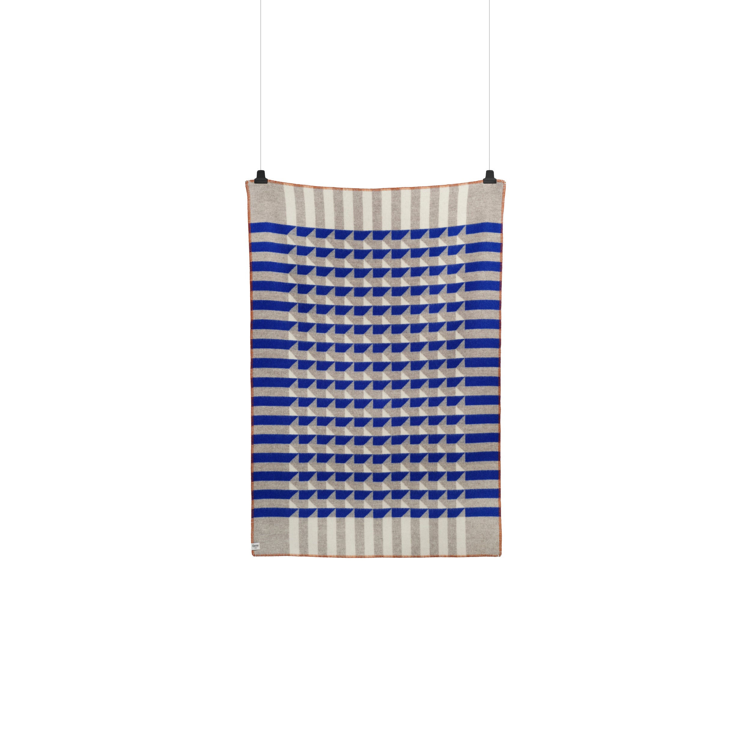 The Kvam Large Throw by Roros features a geometric jacquard weave with bold, horizontal blue and white stripes. The center has a 3D effect in tessellating blue and gray shapes, framed by a thin brown edge.