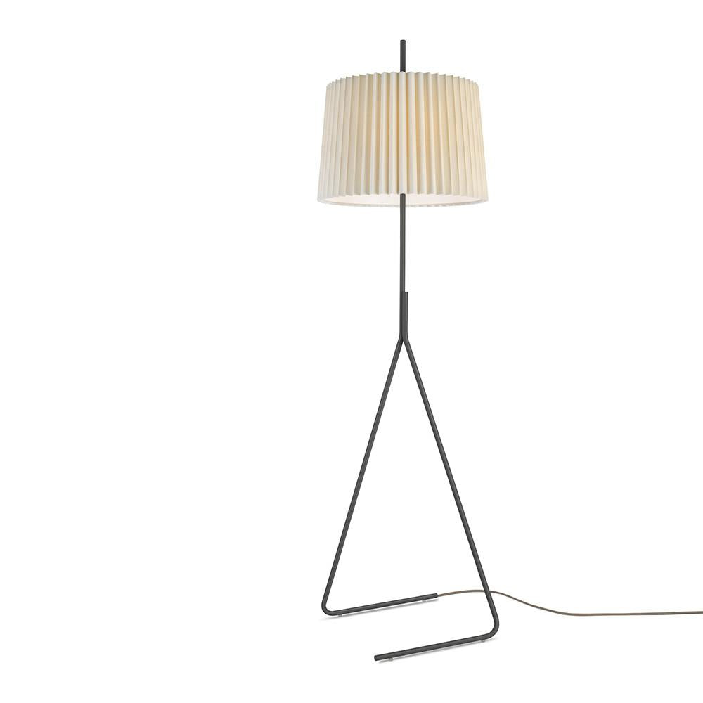 The Fliegenbein BL Floor Lamp by Kalmar features a sleek black metal frame with a triangular base and an elegant ribbed beige cylindrical shade reminiscent of pleated silk, with a visible cord at the bottom for easy access.