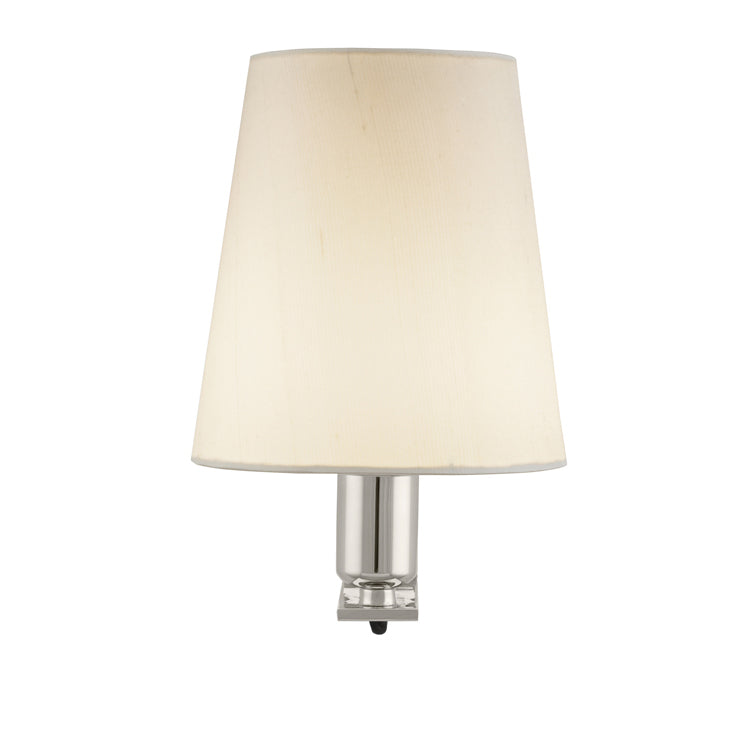 The Krems wall-mounted lamp by Kalmar features a cream-colored conical lampshade and a polished brass base, offering stylish task lighting that elevates any space against a plain white backdrop.