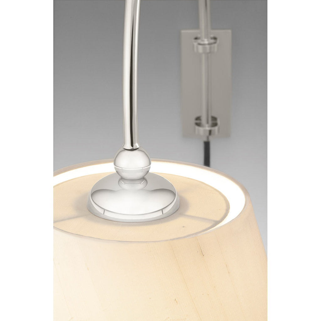 Close-up of the Kalmar Reibe Wall luminaire featuring a cream-colored shade and shiny silver arm. This elegant bedside companion is mounted on a matching silver fixture, highlighting the shades top and polished metal details.