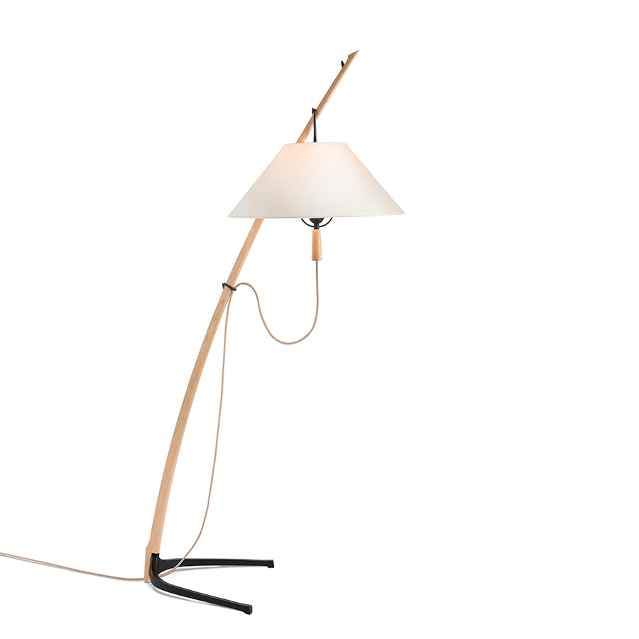 The Kalmar Dornstab Floor lamp, inspired by Wiener Werkbund, features a minimalist design with a slender wooden stand curving upward to a white conical shade. It showcases a black metal base and visible cord.