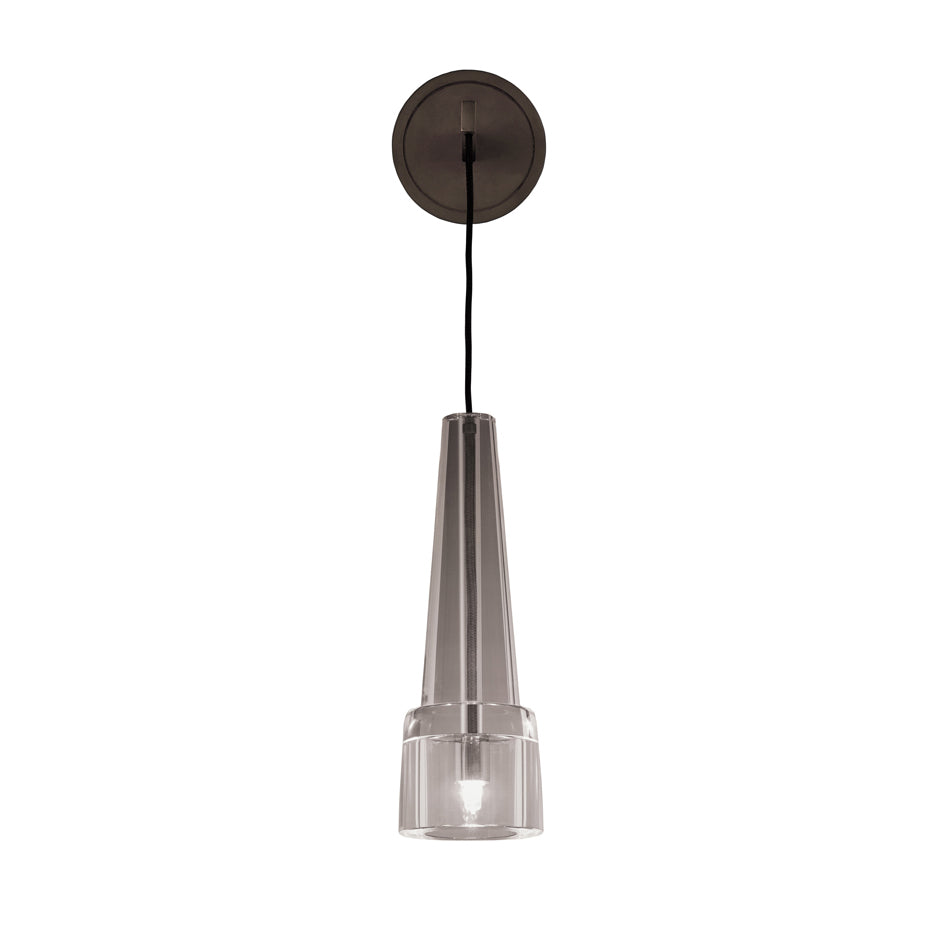 The Keule Wall by Kalmar features a modern, cone-shaped pendant light with a translucent cylindrical bottom and hangs from a black cord. Its attached to a circular black bronze ceiling mount, offering a sleek, minimalist design.