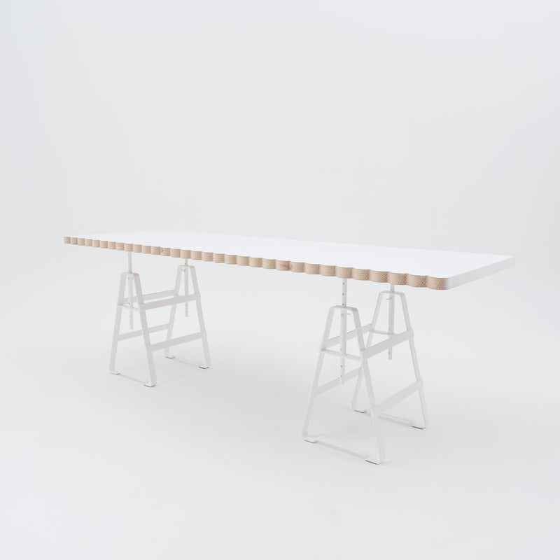 The Lackaffe Trestle by Atelier Haussmann features a minimalist design with a light wood top and powder-coated steel legs. The tabletops undulating edges highlight the elegance typical of Berlin craft producers, set against a white background.