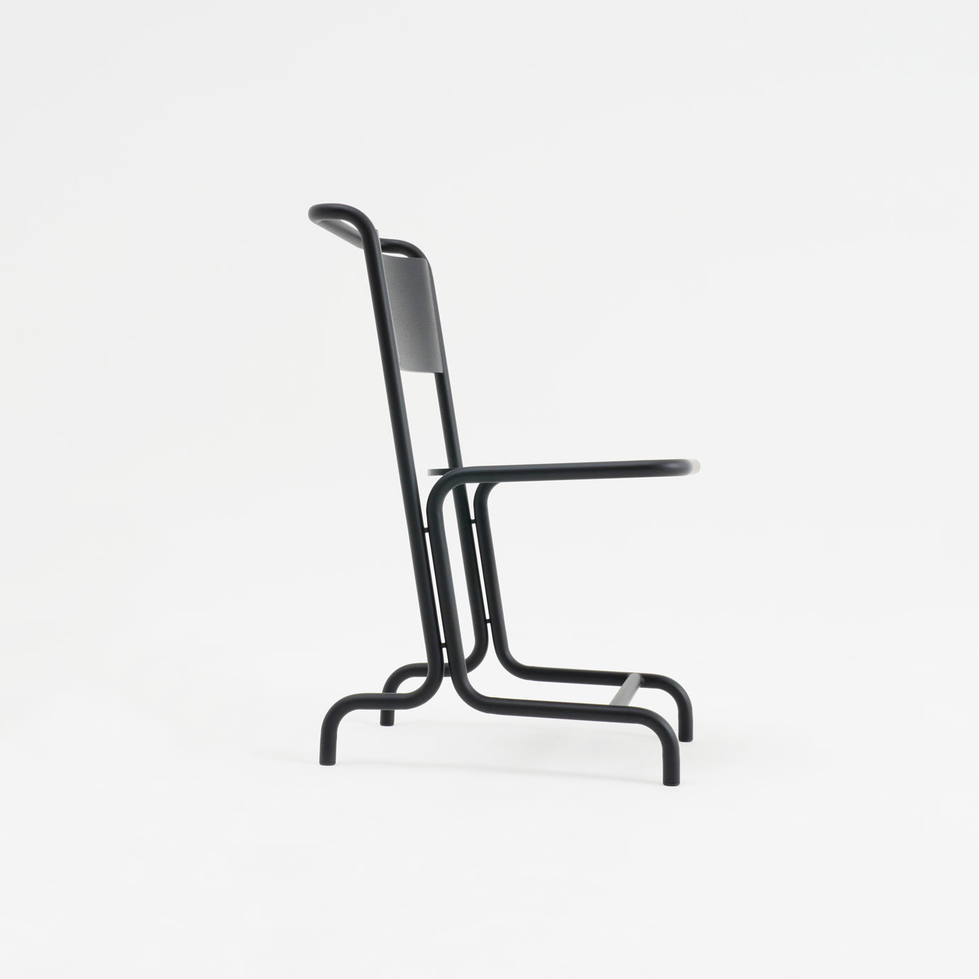 Side view of the László Chair by Atelier Haussmann, a minimalist black cantilever chair featuring a tubular metal frame and flat backrest. The sleek contemporary design on a plain white background highlights its elegant curved steel pipes for enhanced comfort.