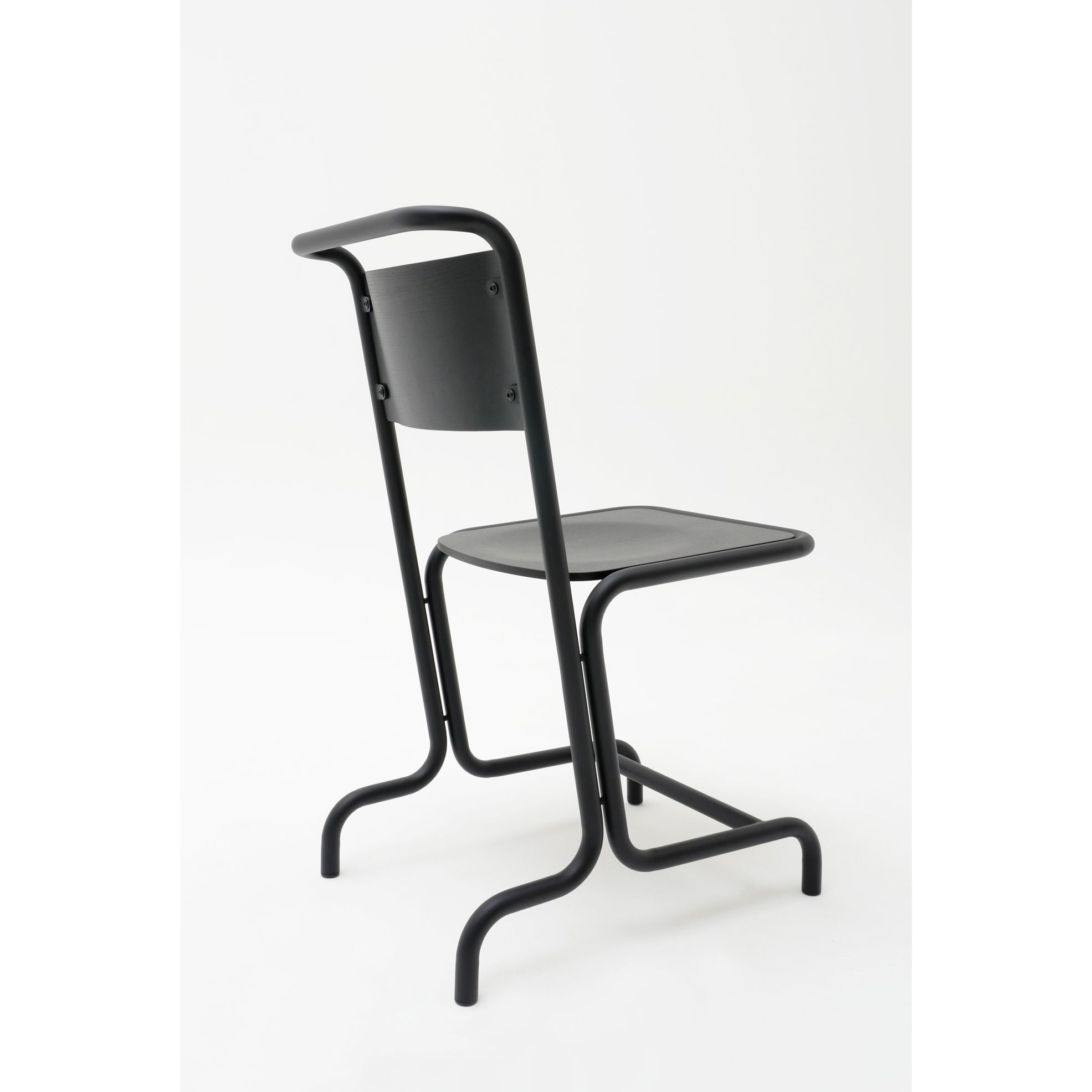 The László Chair by Atelier Haussmann features a sleek, modern black cantilever design with a simple metal frame. It boasts a slightly curved steel pipe backrest, flat seat for comfort, and tubular legs rounded at the base, all presenting a minimalist look against a white background.