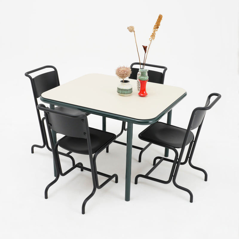 A square table with a light top and dark green legs is surrounded by four Atelier Haussmann László Chairs for comfort. Decorative vases with dried flowers adorn the table, all set against a plain white backdrop.