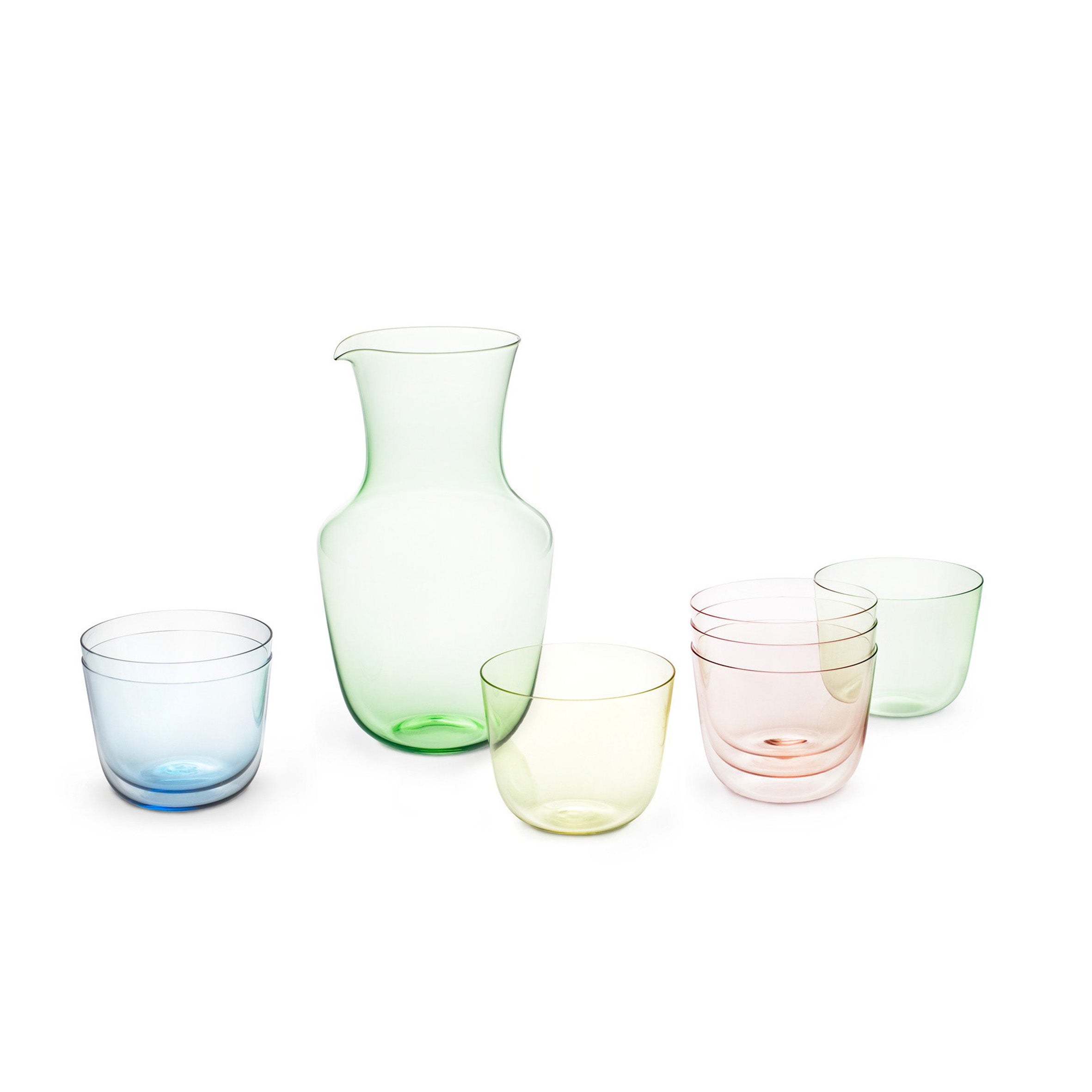 The Alpha Water Tumbler collection by Lobmeyr, made of elegant pastel-colored, mouth-blown lead-free crystal, includes a green pitcher and six stackable blue, green, and pink glasses, all beautifully displayed on a white background.