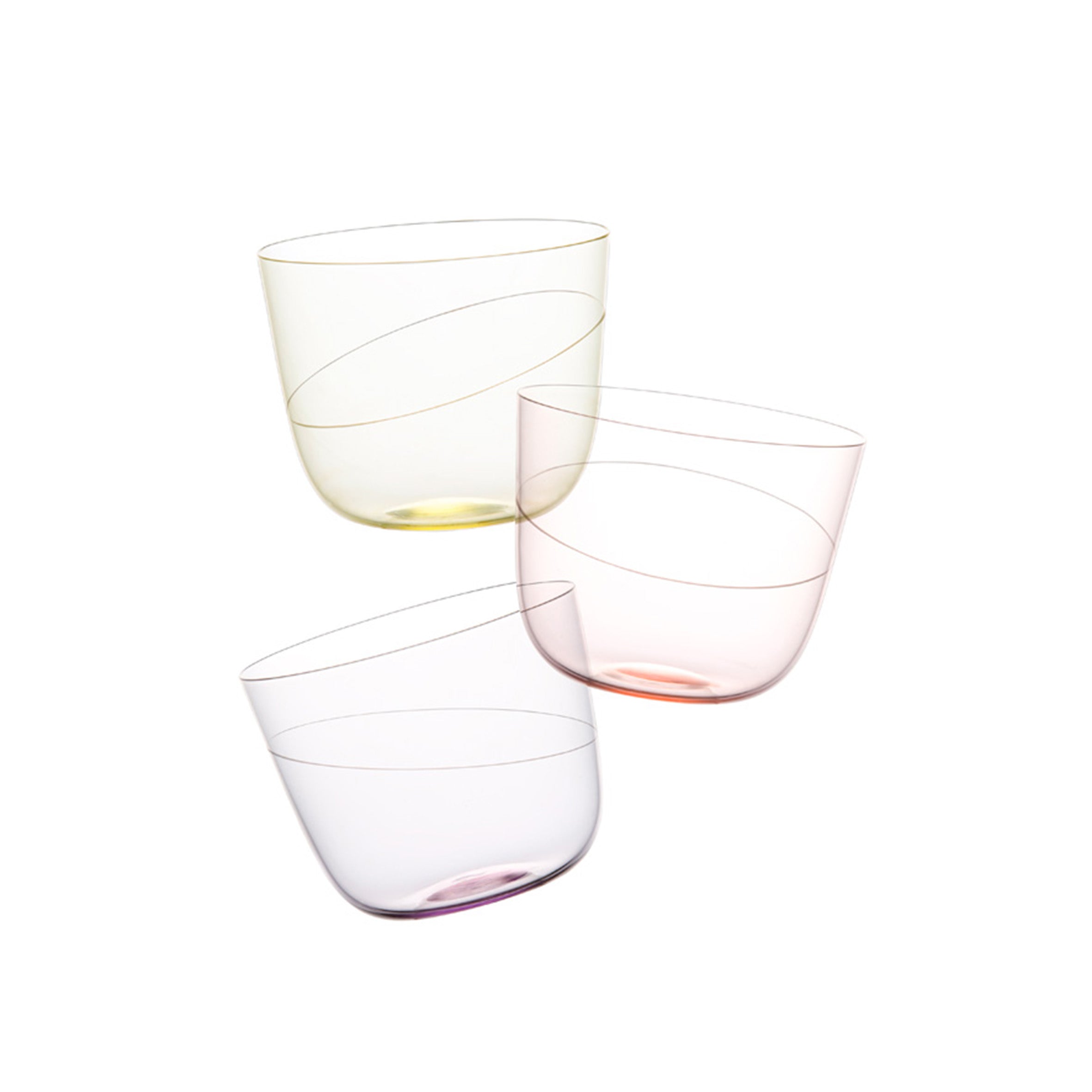 Three Lobmeyr Alpha water tumblers, with subtle pastel hues of yellow, pink, and purple, are artfully arranged against a plain white background. Each mouth-blown crystal glass features an engraved ellipse design and angled top edge, showcasing intricate craftsmanship.