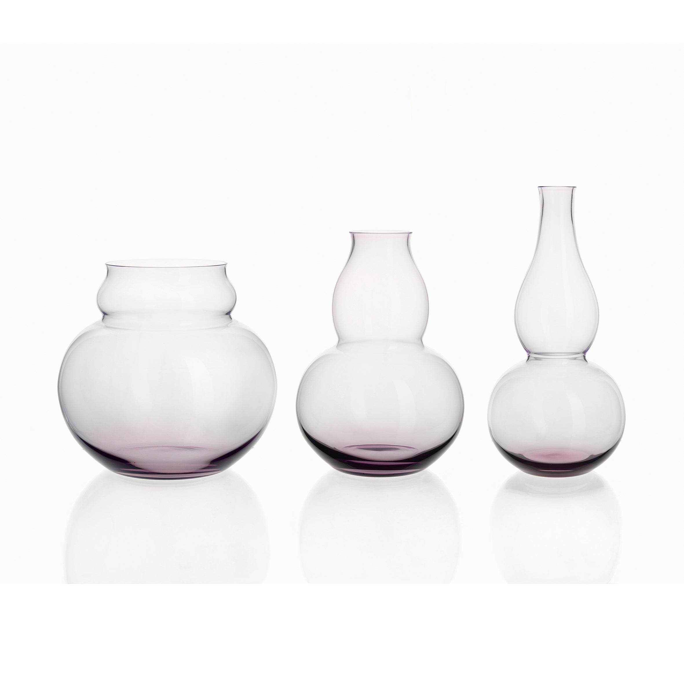 The Lobmeyr BV71 Calabash Flower Vases, with elegant gourd-inspired shapes and a subtle purple hue at the base, are arranged side by side against a plain white background.