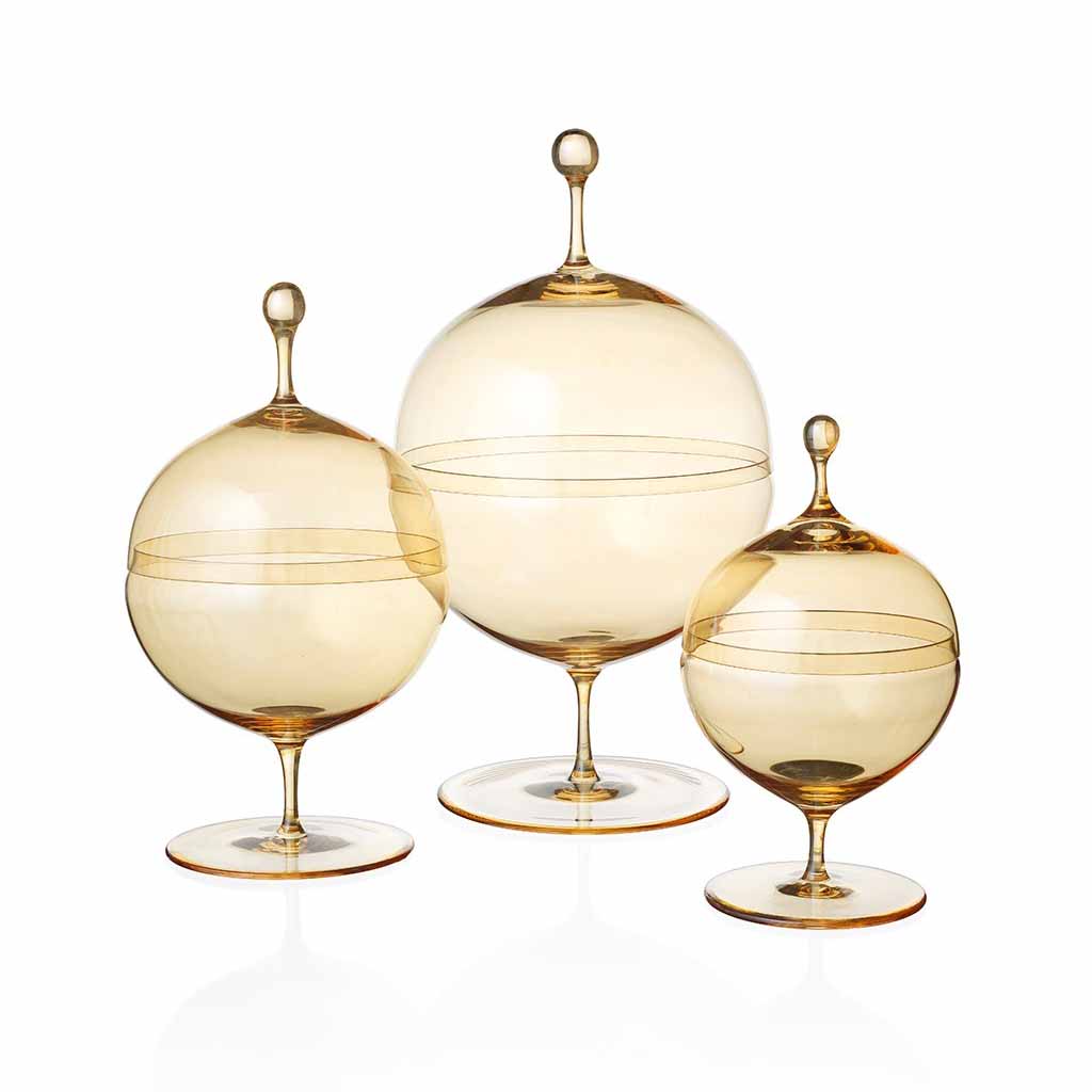 Three Candy Dish Gold Lustre pieces by Lobmeyr, featuring amber glass with rounded bodies and tapered lids on pedestal bases in various sizes. These mouth-blown, lead-free crystal dishes are translucent and reflect light beautifully, showcasing a design reminiscent of Oswald Haerdtls craftsmanship.
