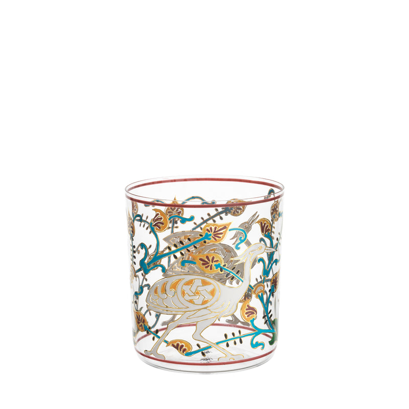 The Alhambra DOF Tumbler by Lobmeyr is a clear glass vessel with gold and colored designs, inspired by the Alhambra palace. It features birds, foliage, and red, blue, and green accents hand-painted on crystal for an elegant decorative look.