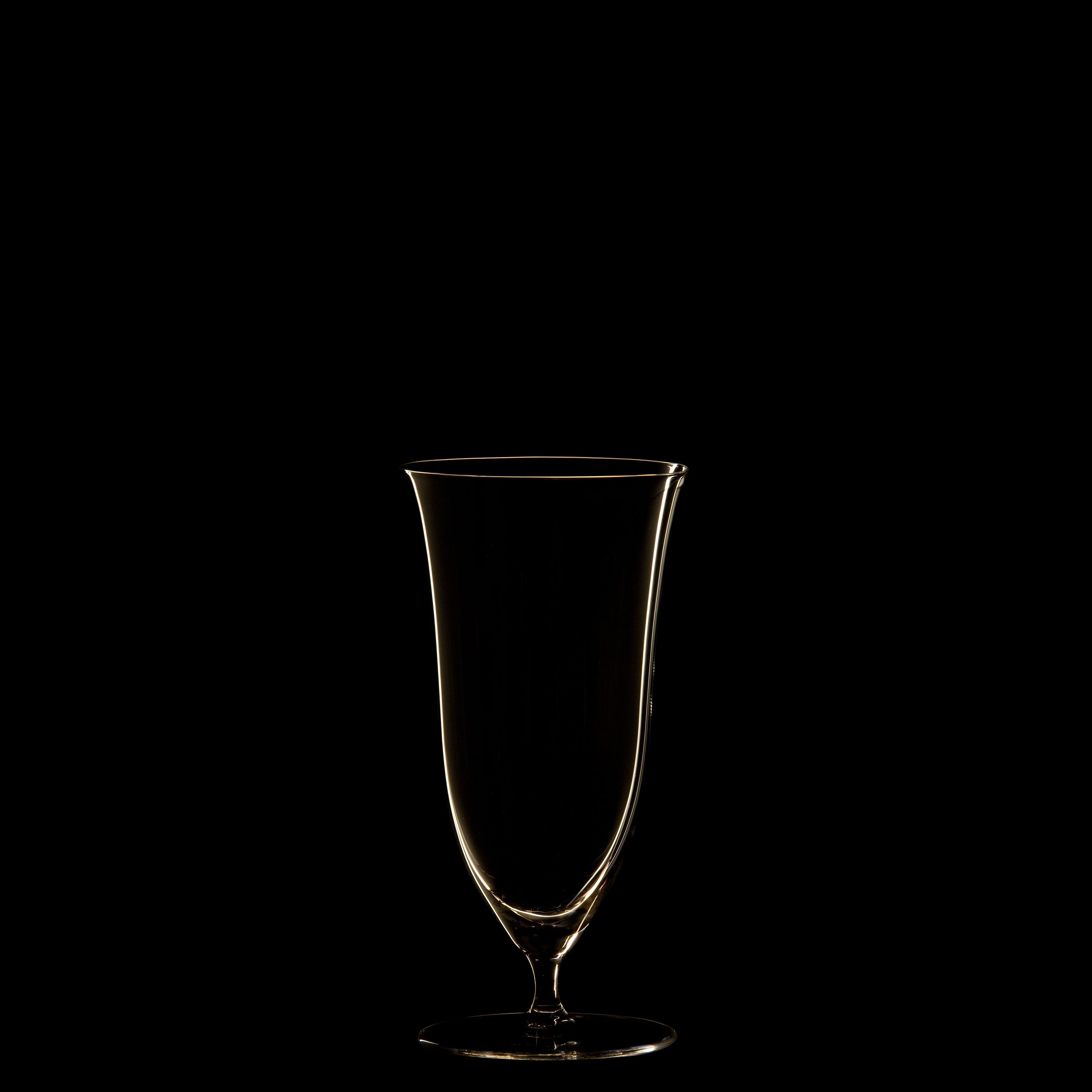 The Patrician Drinking Set No. 238 from Lobmeyr features a tall, elegant wine glass made of mouth-blown crystal, showcased against a black background with lighting that highlights its smooth contours and delicate shape.