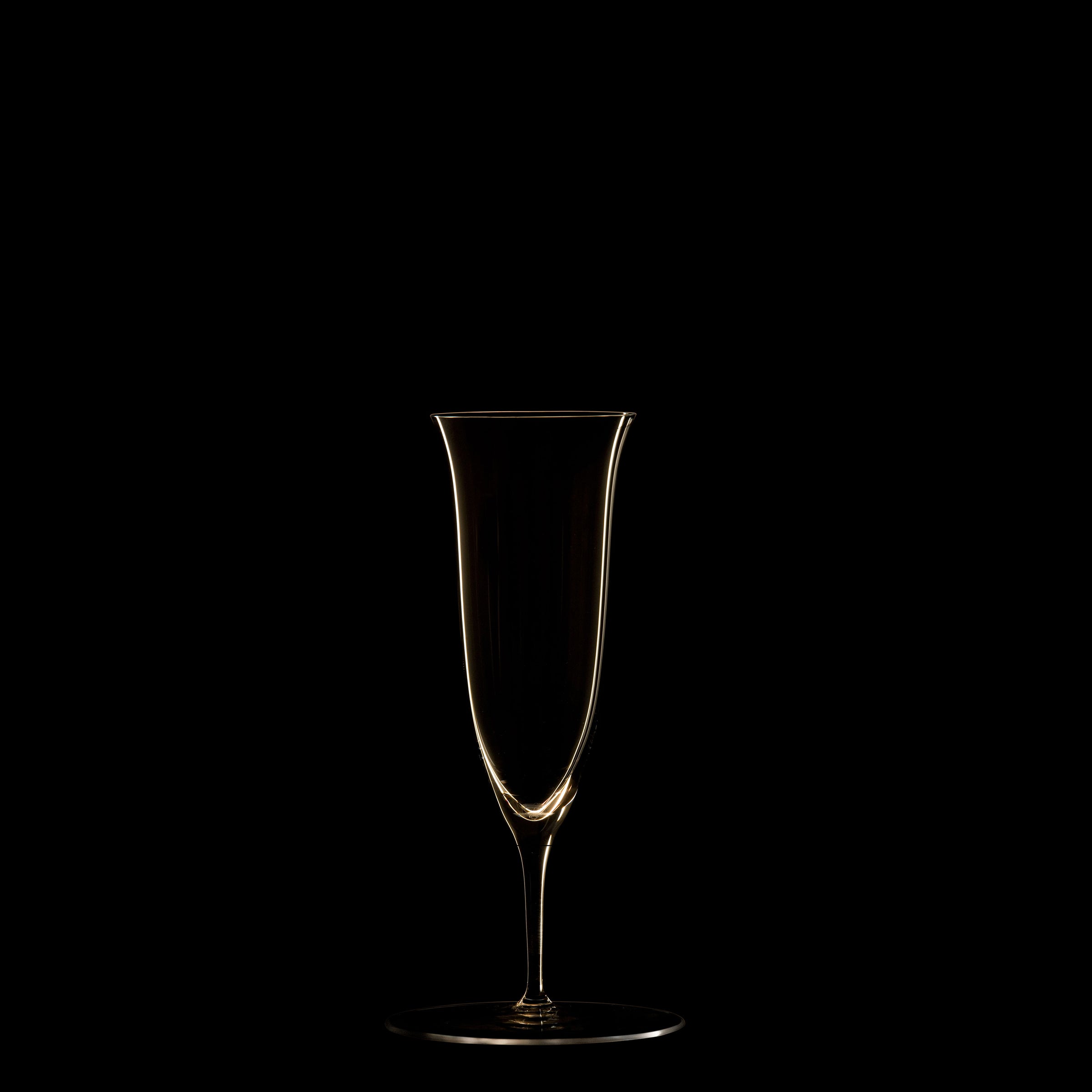 The Lobmeyr Drinking Set No. 238 - Patrician features an elegant, thin champagne flute crafted from mouth-blown crystal. Situated against a black background, its delicate silhouette and smooth curves are highlighted, with the glass appearing empty.