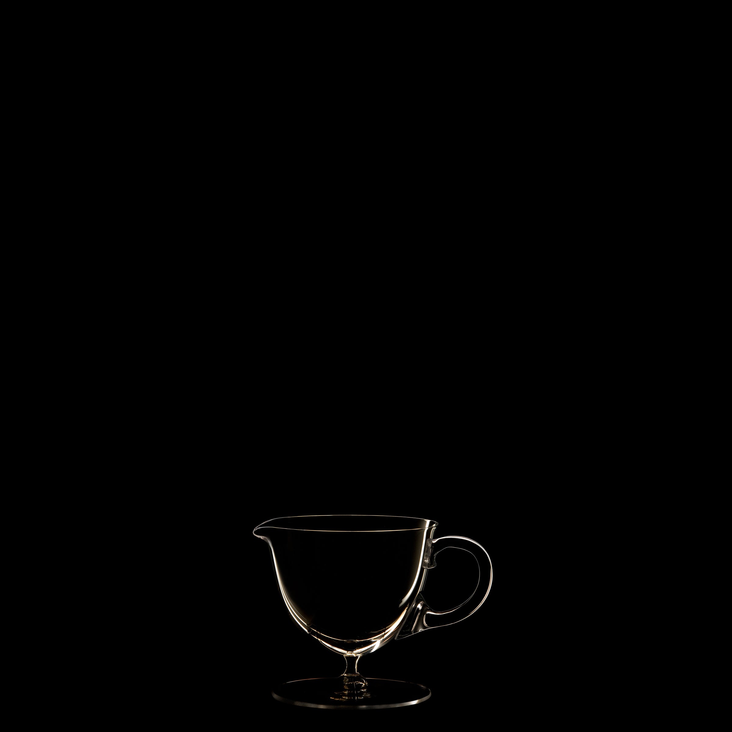 Against a black background, the delicate contours of Lobmeyrs Drinking Set No. 238 - Patrician are illuminated, evoking the minimalistic elegance of Josef Hoffmanns designs and reflecting the refined craftsmanship of Wiener Werkstätte.